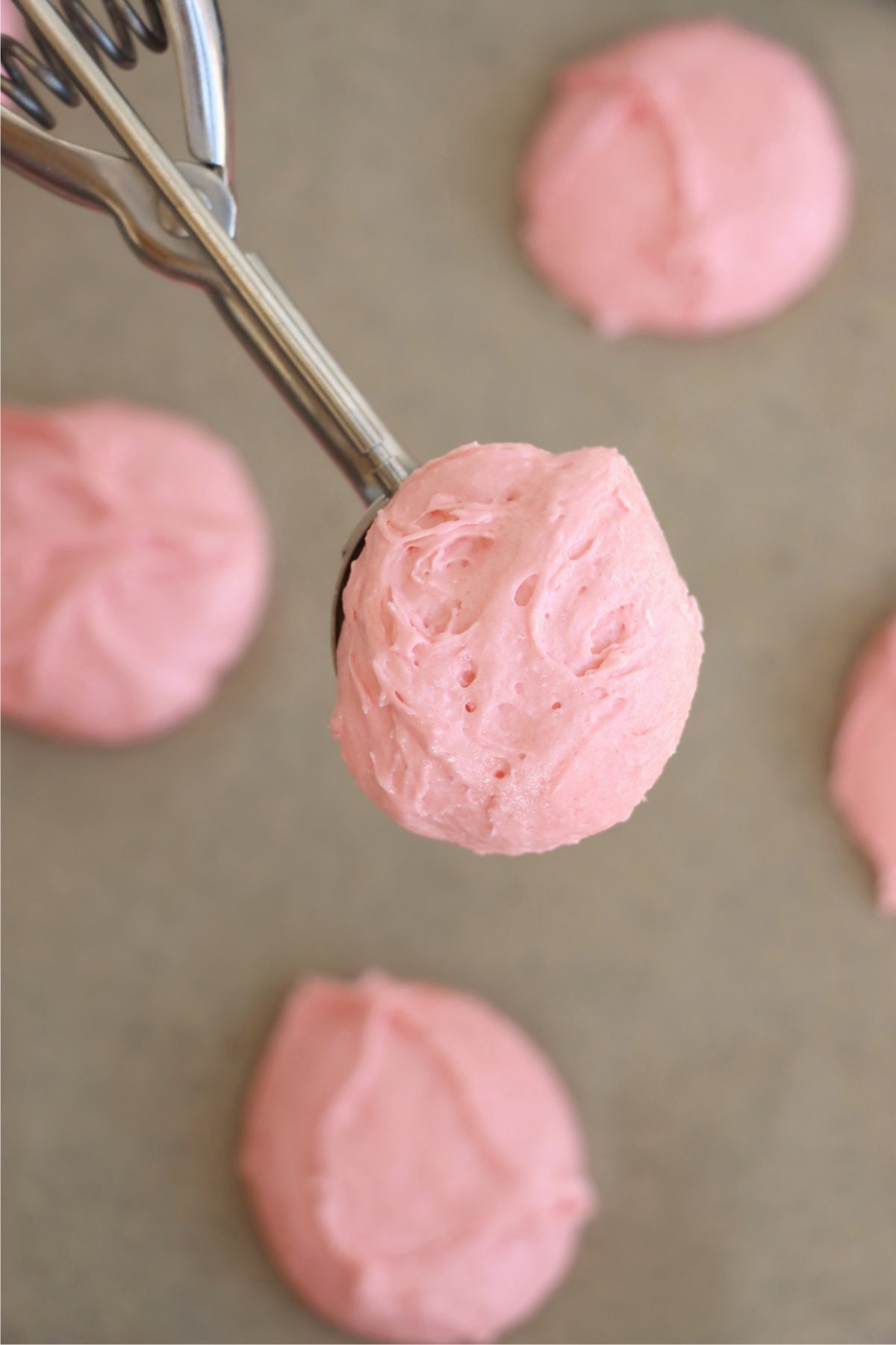 A cookie dough scoop filled with smooth and fluffy pink strawberry dough, ready to be shaped into cookies.