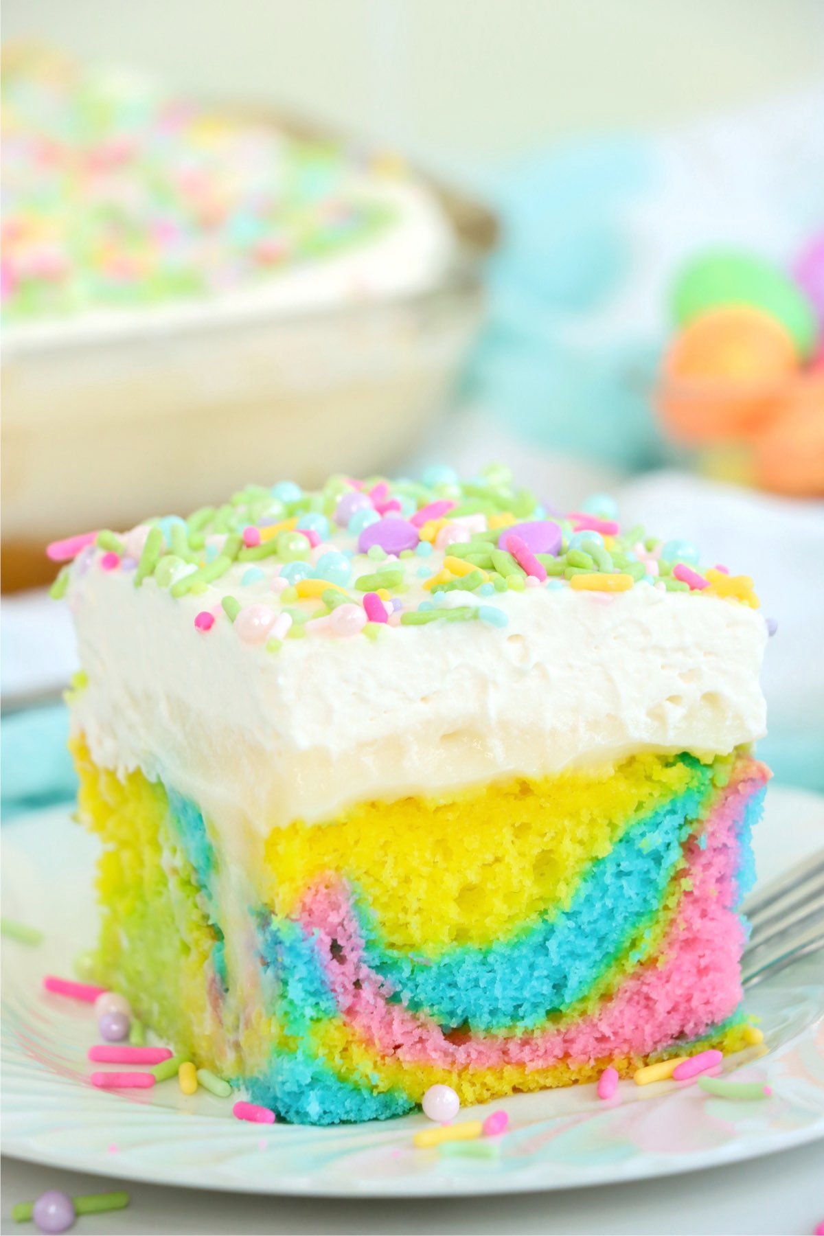 A perfect side view of a soft and moist Easter Poke Cake slice, showcasing its colorful interior and creamy layers.