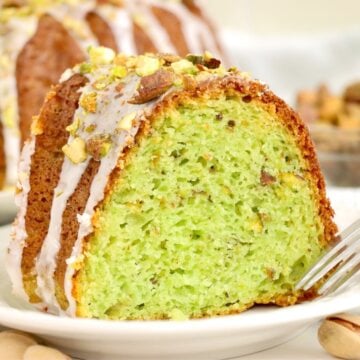 A single slice of pistachio bundt cake on a white plate, showing its vibrant green interior and nutty texture.