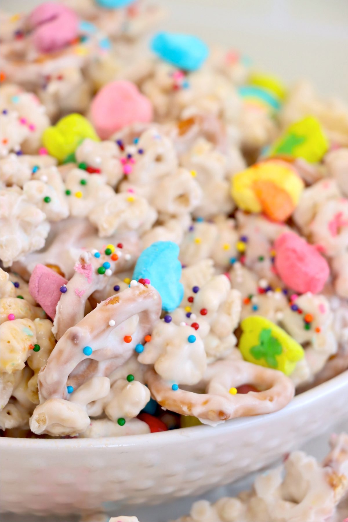 A bowl of St. Patrick’s Day snack mix with vanilla-coated pretzels, Chex, and colorful marshmallows.