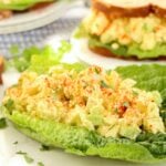 Fresh tofu salad nestled in a romaine lettuce leaf, surrounded by sandwich ingredients and garnishes.