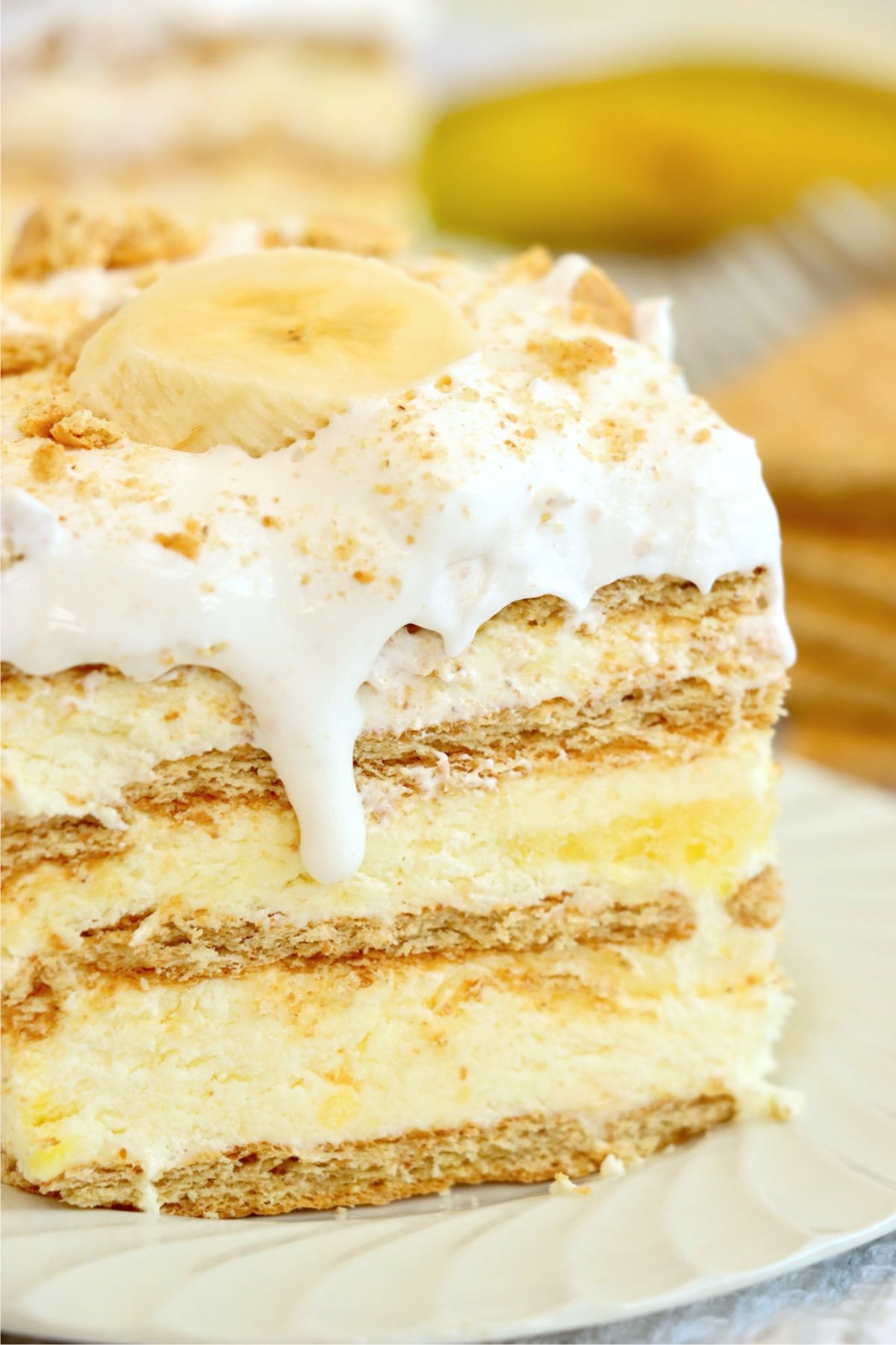 Slice of Banana Pudding Icebox Cake on a white plate, showing off its creamy layers and banana garnish.
