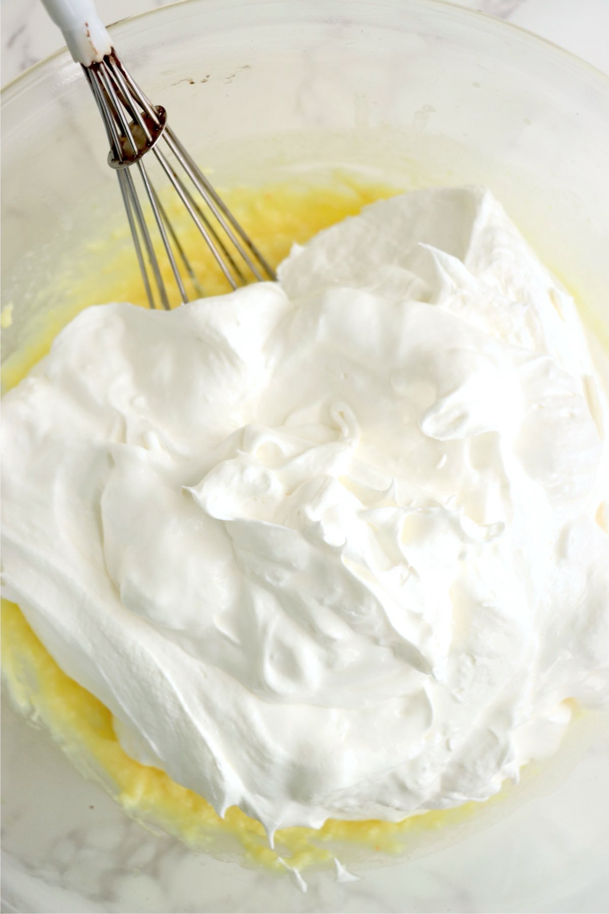 Whipped topping added to the banana pudding mixture, ready to be folded into a smooth and fluffy filling.