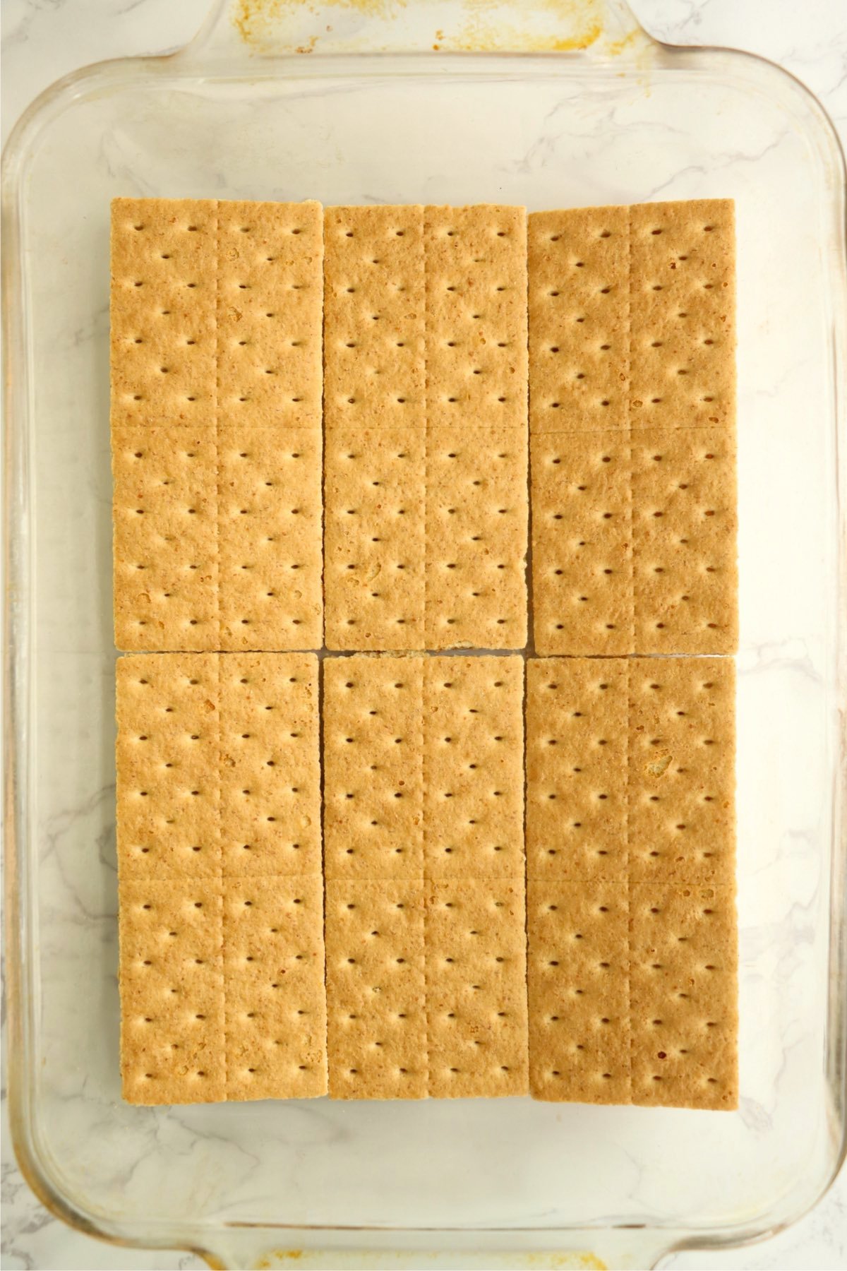 Layer of graham crackers laid in a glass baking dish.