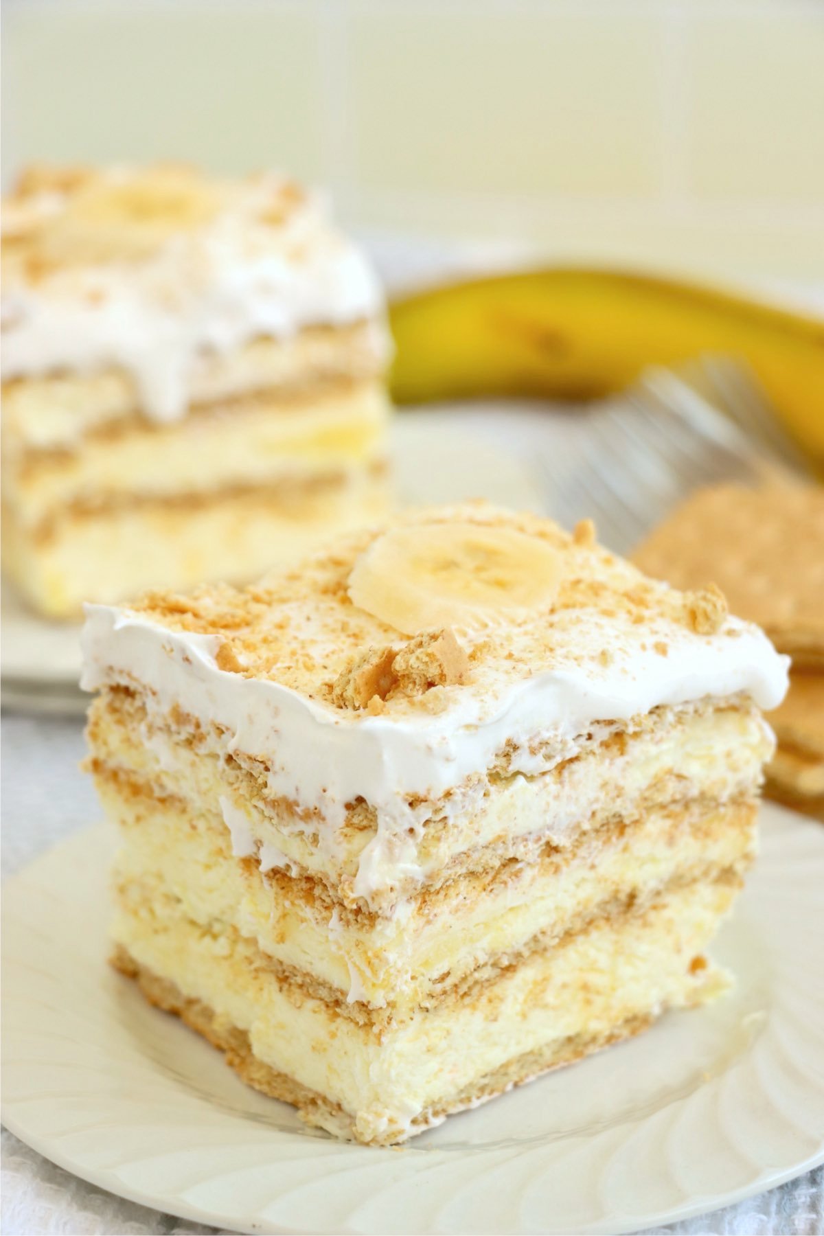 A creamy banana pudding icebox cake slice layered with graham crackers and whipped topping.
