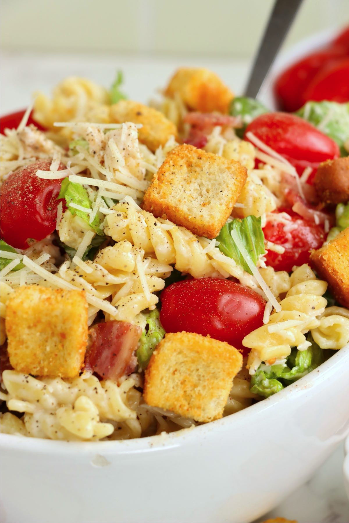 Close-up of the pasta salad, highlighting croutons, cherry tomatoes, lettuce, and pasta with Caesar dressing.