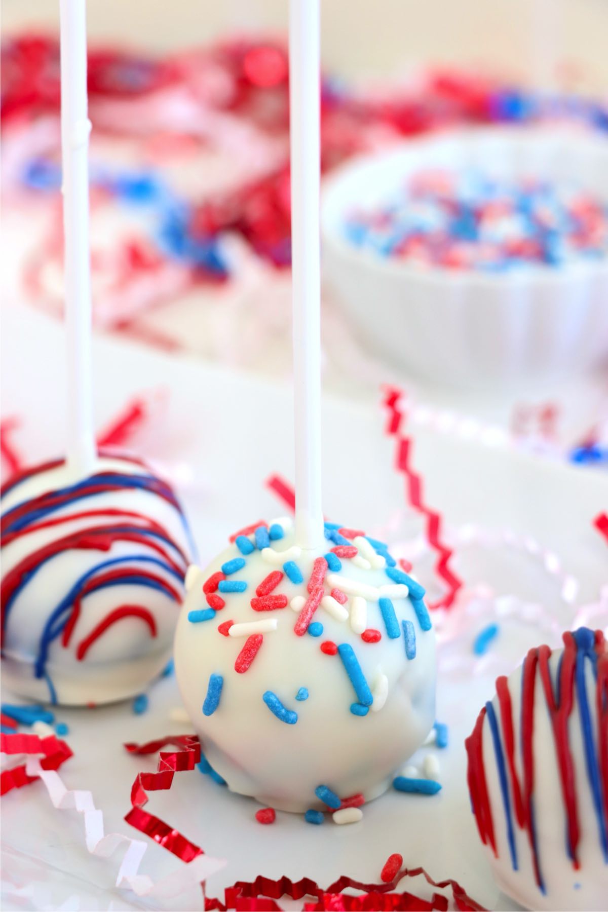 Close view of red, white, and blue drizzled cake pops ready to serve.