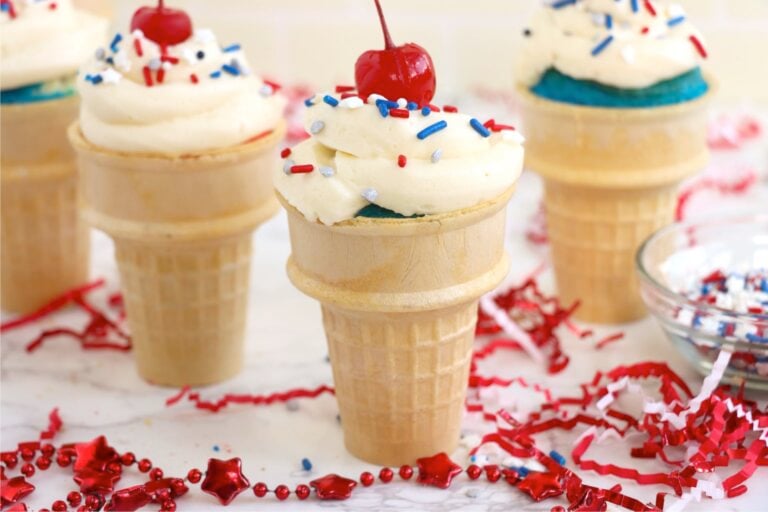 Group of frosted cupcake cones arranged on a table with red and white decorations.