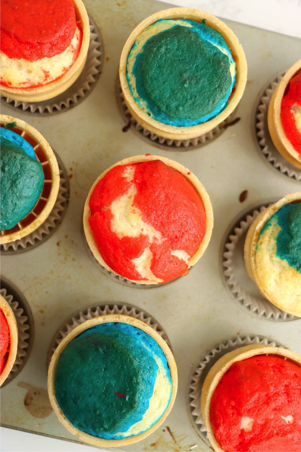 Baked cupcakes inside ice cream cones with colorful red, white, and blue tops.