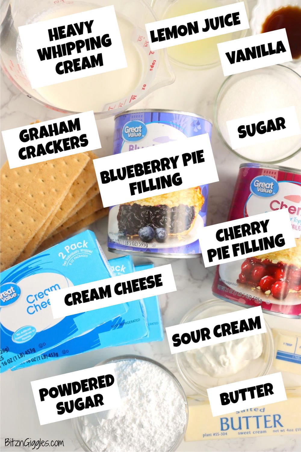All cheesecake ingredients laid out on a white surface, including cream cheese, graham crackers, sugar, and pie fillings.
