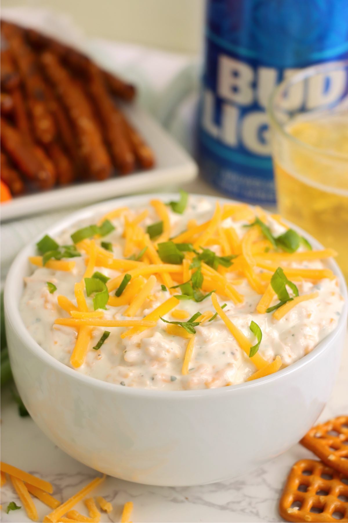 Finished ranch beer dip in a bowl topped with shredded cheese and green onions.