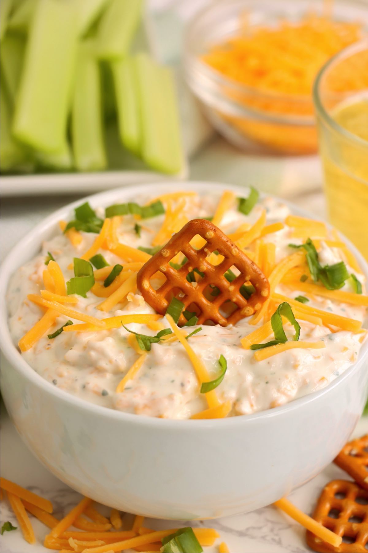 Ranch beer dip served with a pretzel placed in the center and garnished with cheese and green onions.