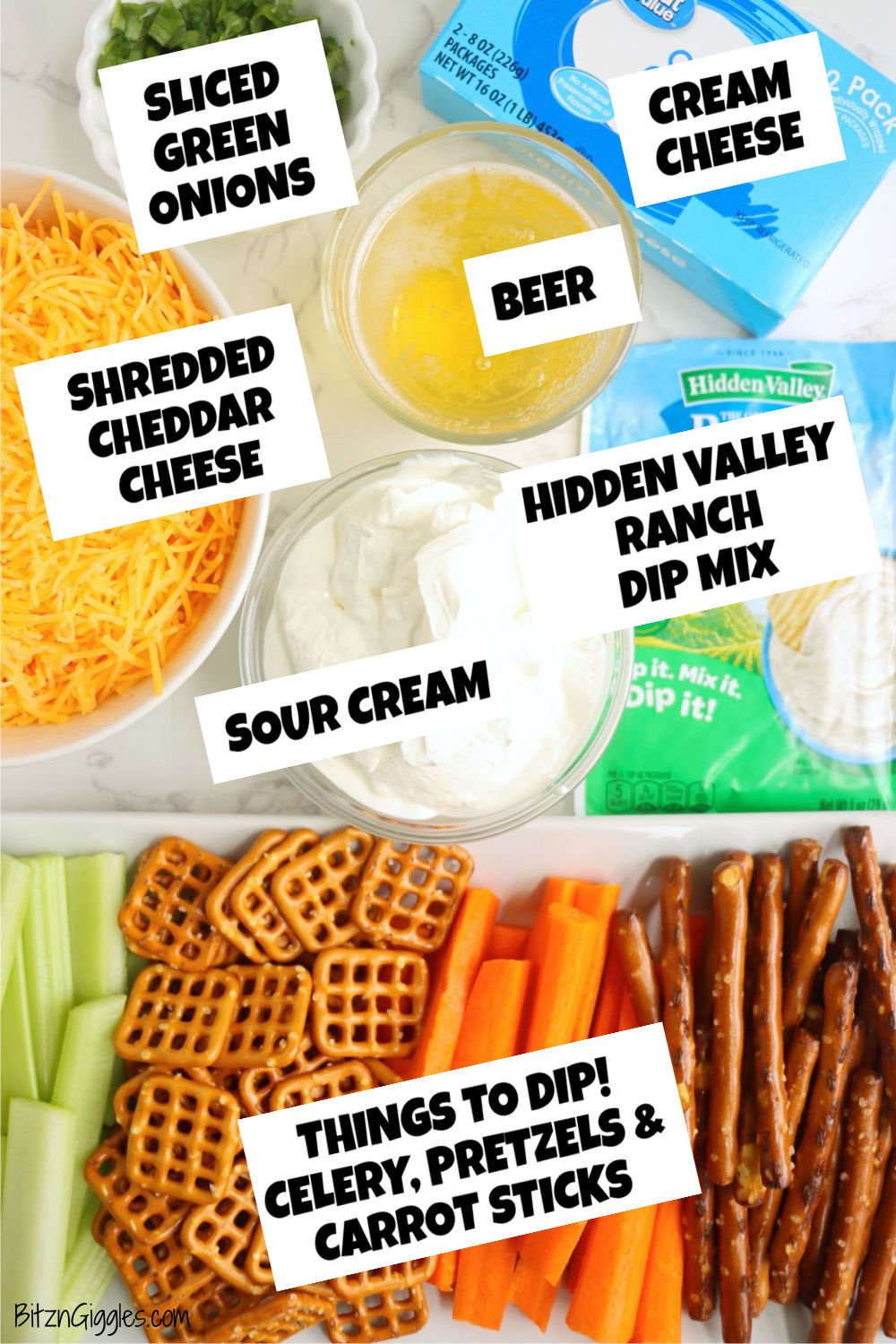 Ingredients for ranch beer dip arranged on a white table, including cheese, sour cream, cream cheese, ranch mix, beer, veggies, and pretzels.