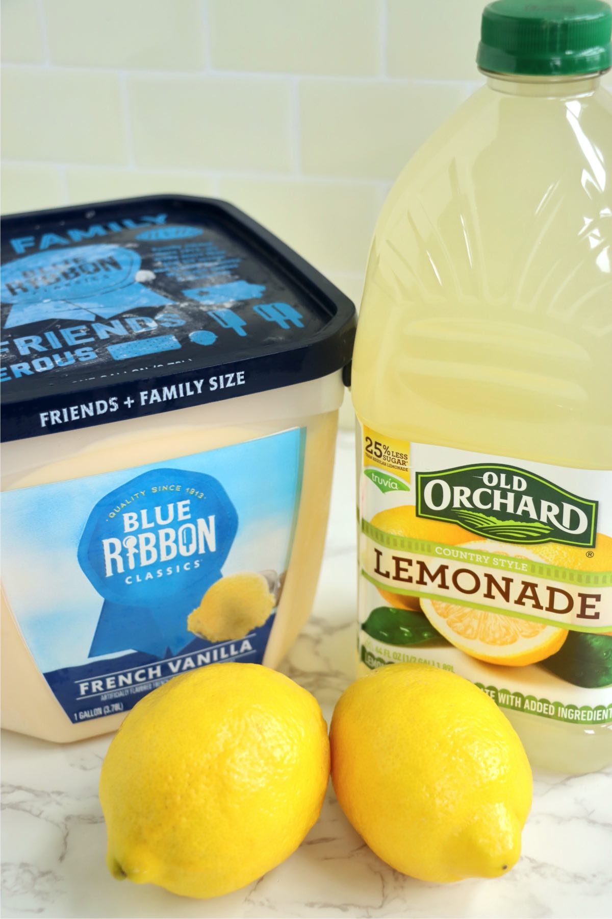 Vanilla ice cream, lemonade, and fresh lemons on a countertop.