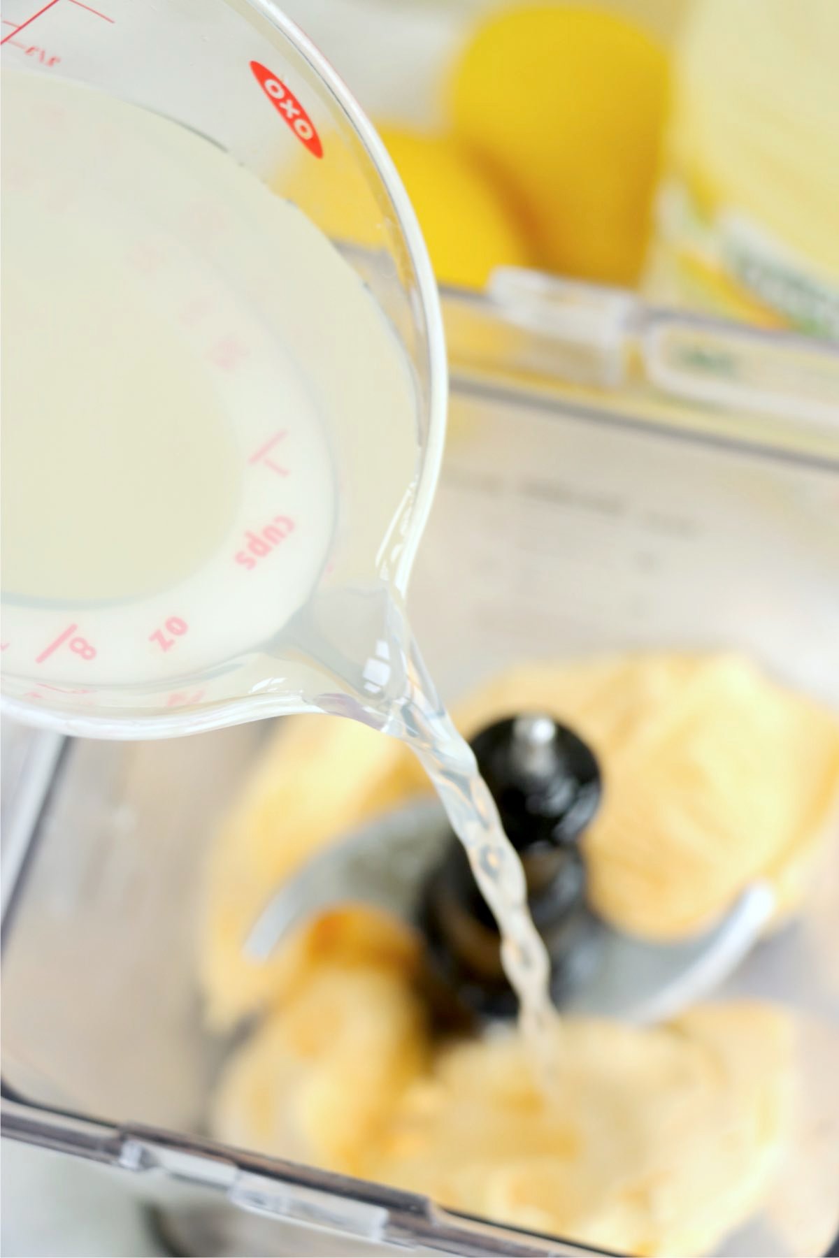 Lemonade being poured into a blender with scoops of vanilla ice cream.