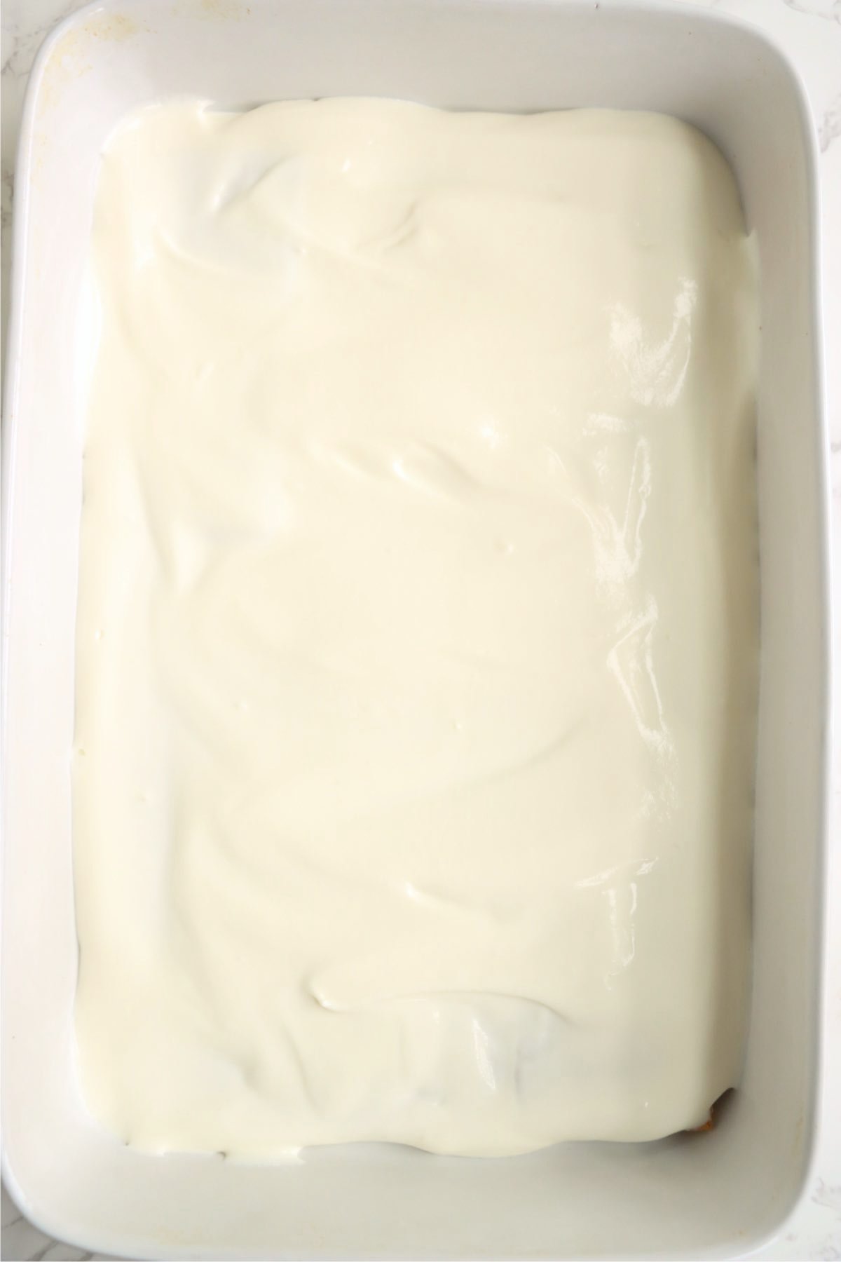 Creamy pudding mixture smoothly spread over a graham cracker layer in a white rectangular baking dish.