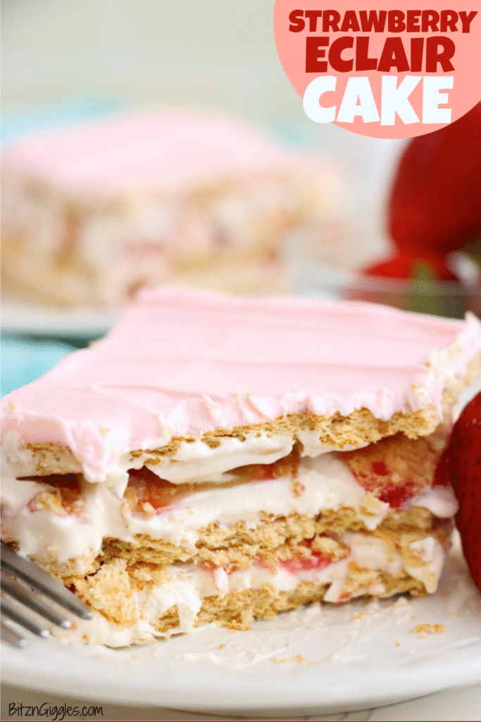 A dessert showcasing layers of graham crackers, creamy filling, fresh strawberries, and topped with smooth pink frosting, served on a plate with a fork and a strawberry garnish.