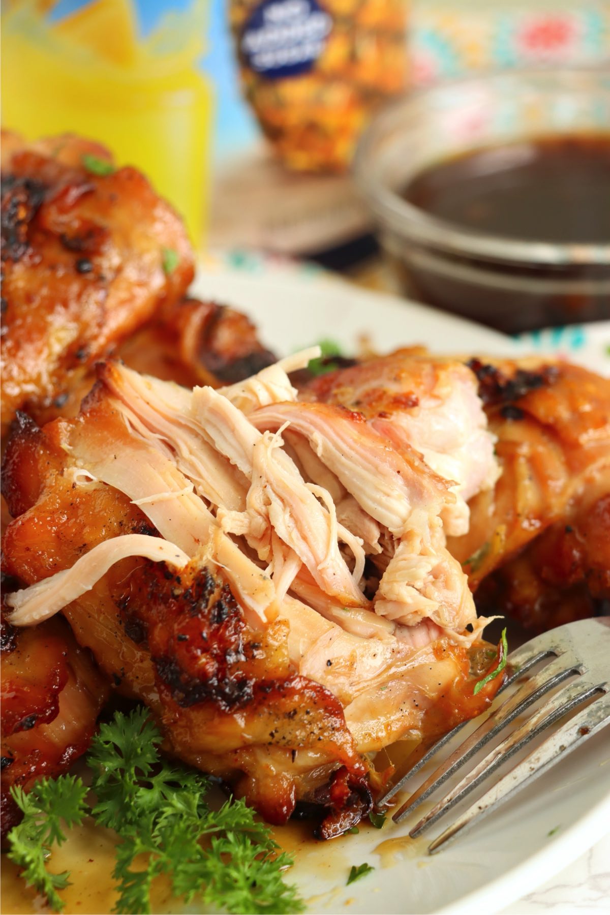 Grilled chicken being shredded with a fork, showing how juicy and tender it is.