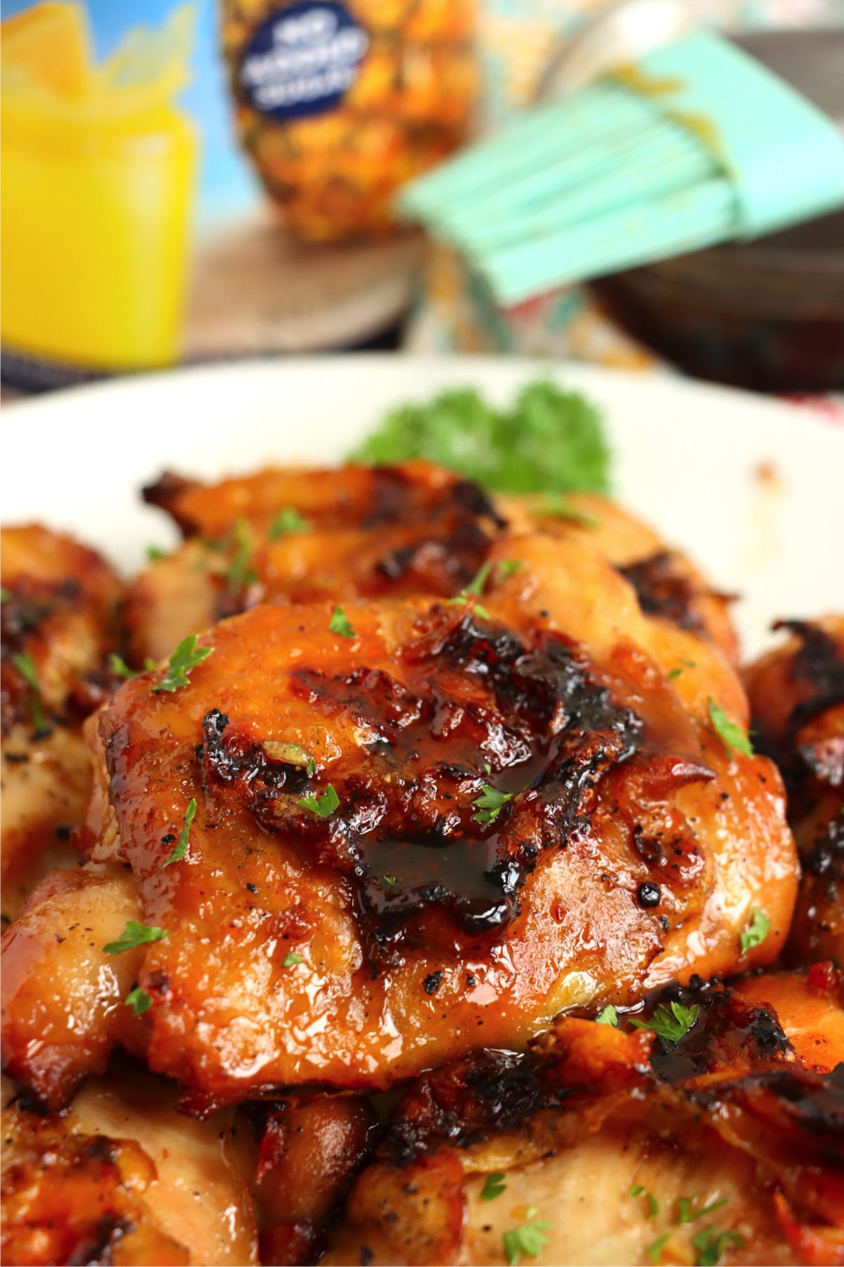 Chicken thighs glazed with a sweet and savory sauce, garnished with fresh parsley and served on a white platter.