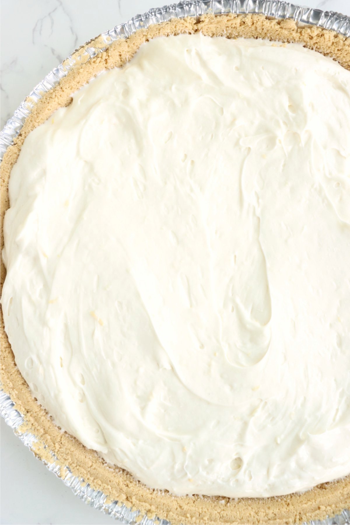 Creamy mixture spread inside a graham cracker pie crust.