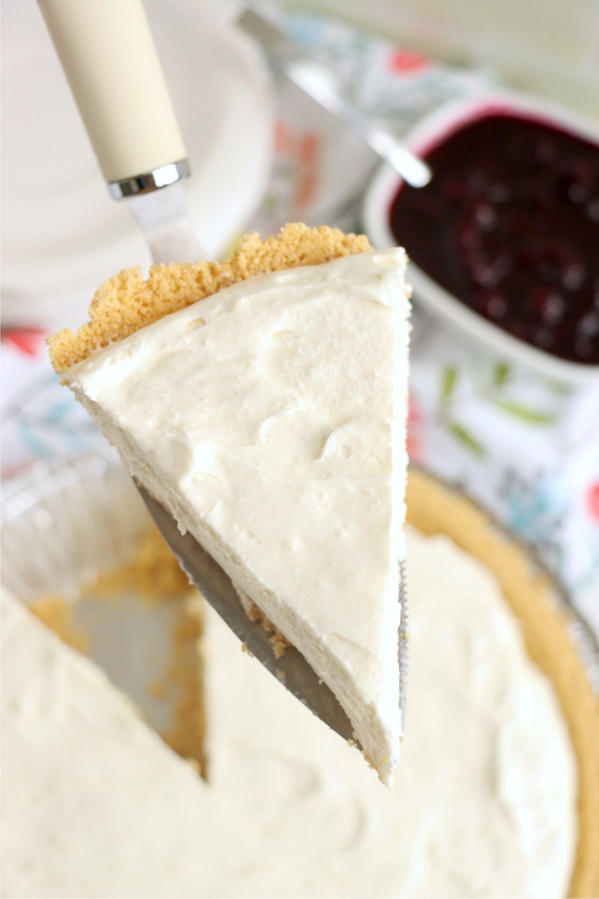 A slice of pie being lifted from a full pie in a graham cracker crust.
