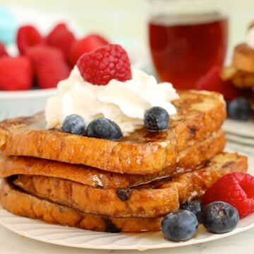 French toast topped with whipped cream, blueberries, and a raspberry.