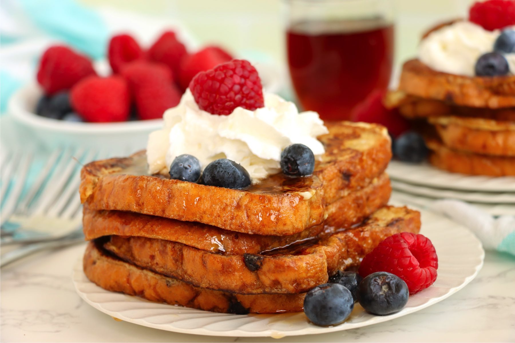French toast topped with whipped cream, blueberries, and a raspberry.