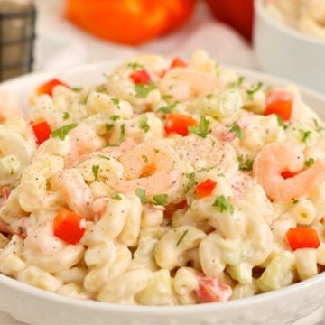 Large bowl of shrimp pasta salad garnished with parsley and black pepper.