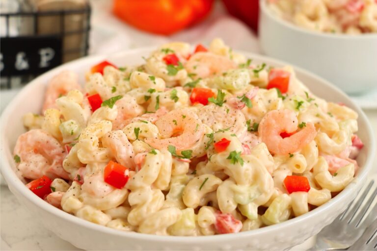 Large bowl of shrimp pasta salad garnished with parsley and black pepper.