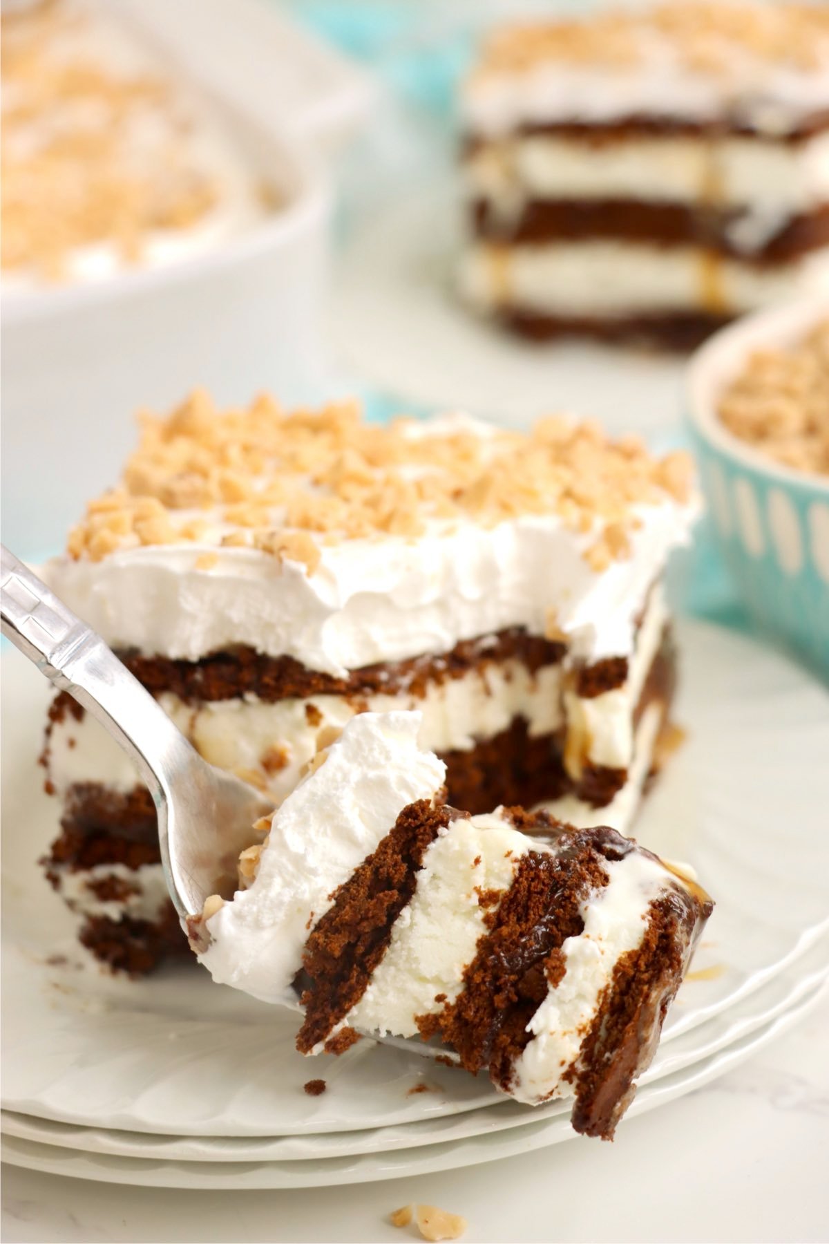 A bite of layered ice cream sandwich dessert lifted by a fork, revealing creamy and chocolatey layers.