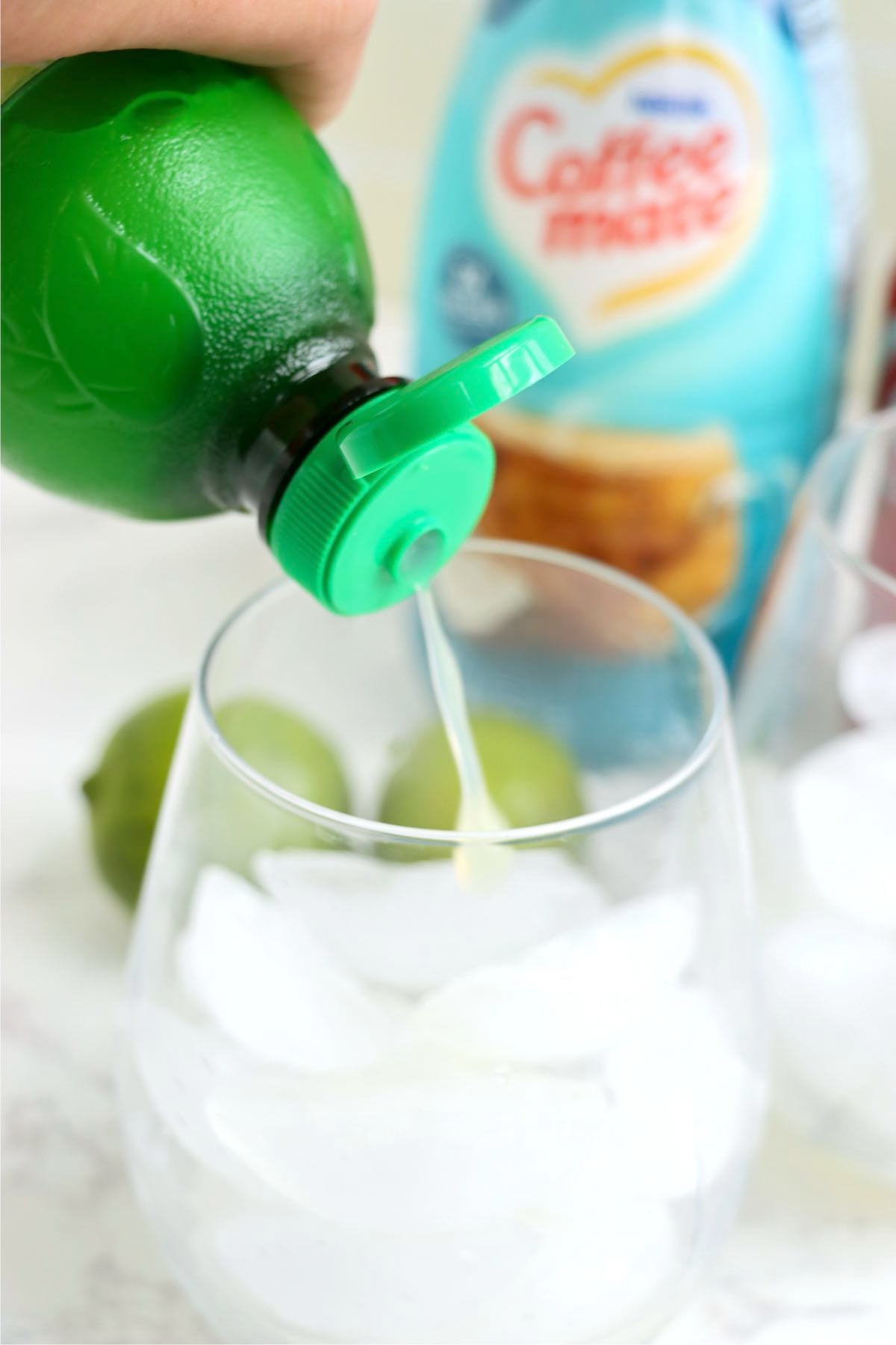 Pouring lime juice into a glass filled with ice.