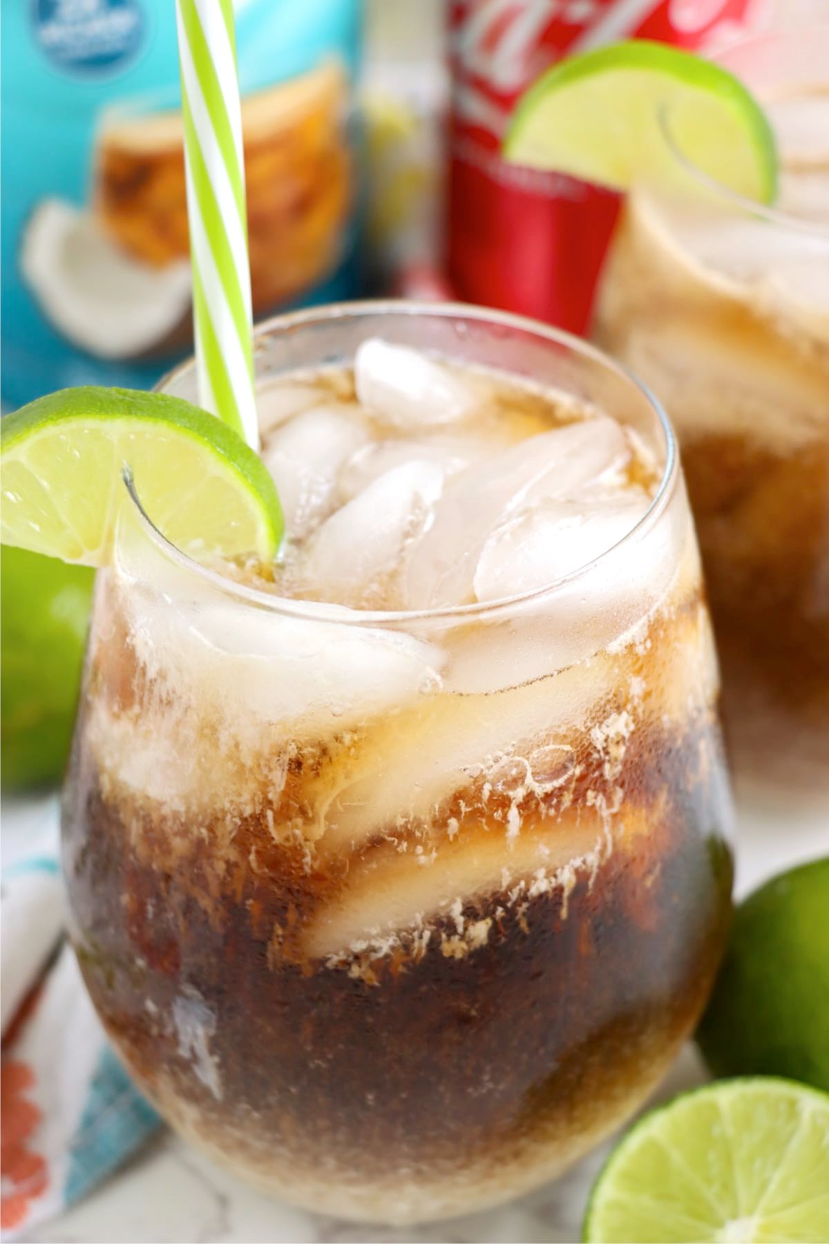 Close-up of a fizzy drink with a lime wedge and striped straw.