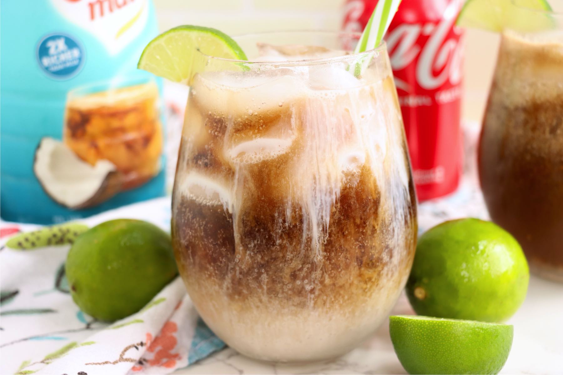 Iced drink garnished with a lime wedge and green striped straw.