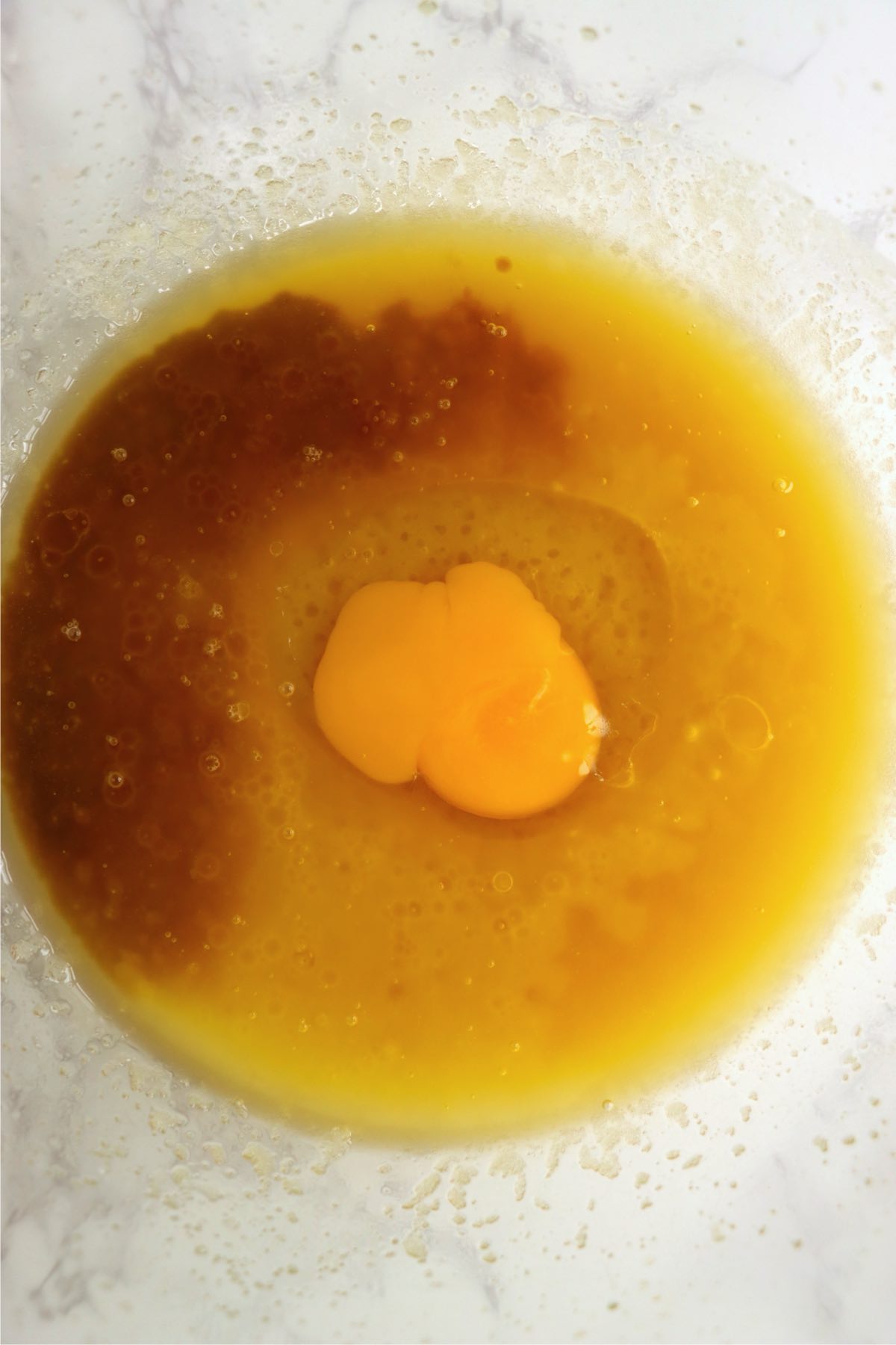 An egg and vanilla added into the bowl of butter and sugar.