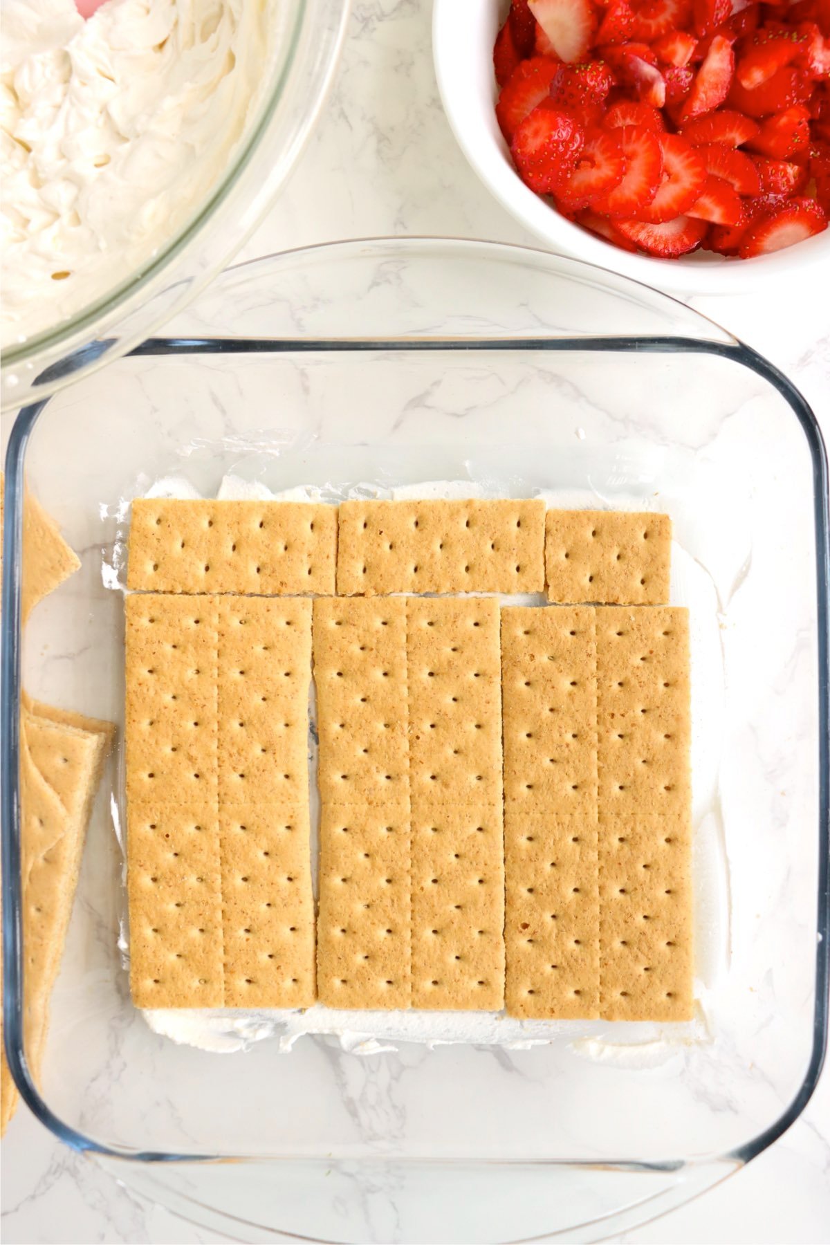 Layer of graham crackers arranged over whipped cream in the dish.