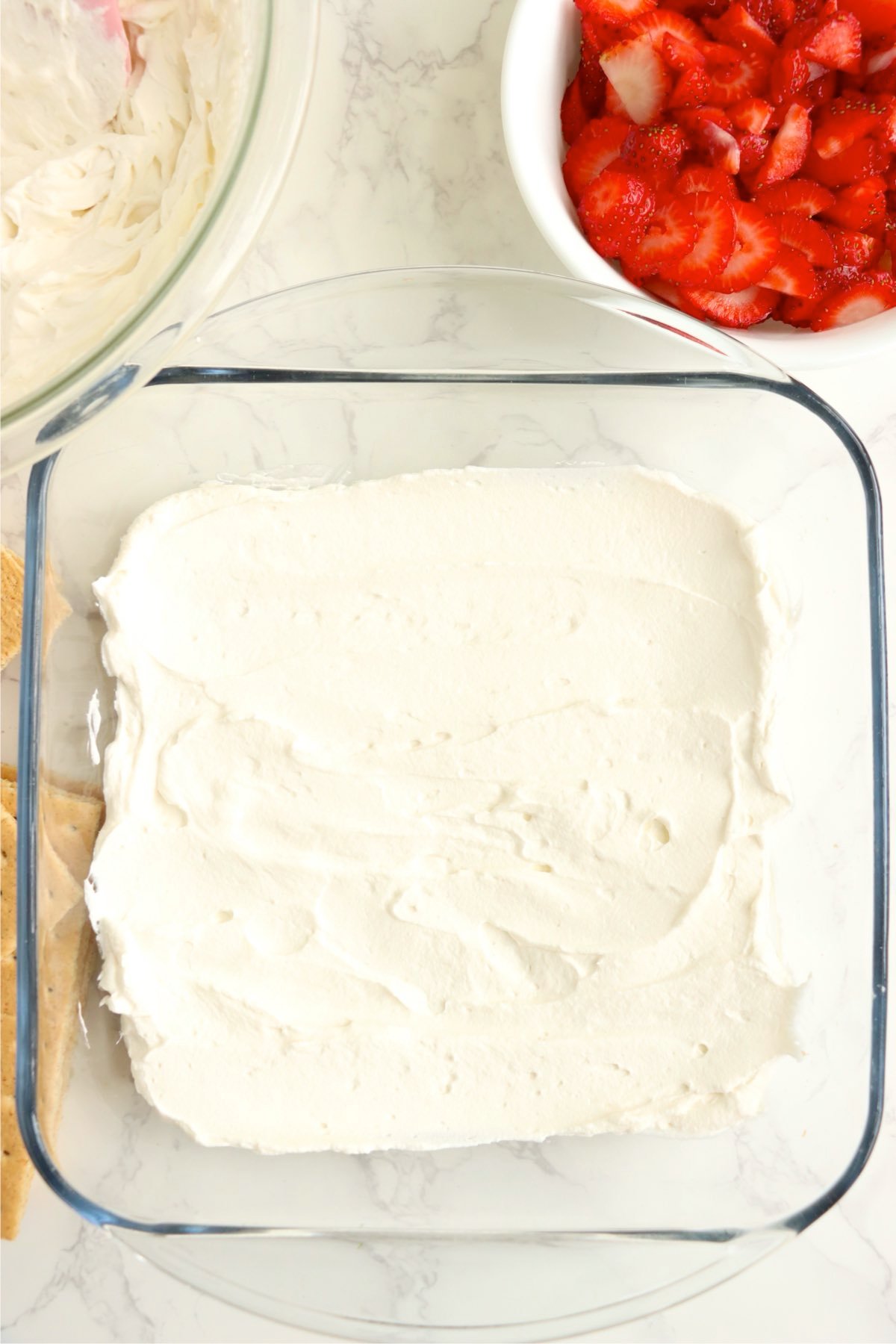 Layer of whipped cream spread smoothly over graham crackers.