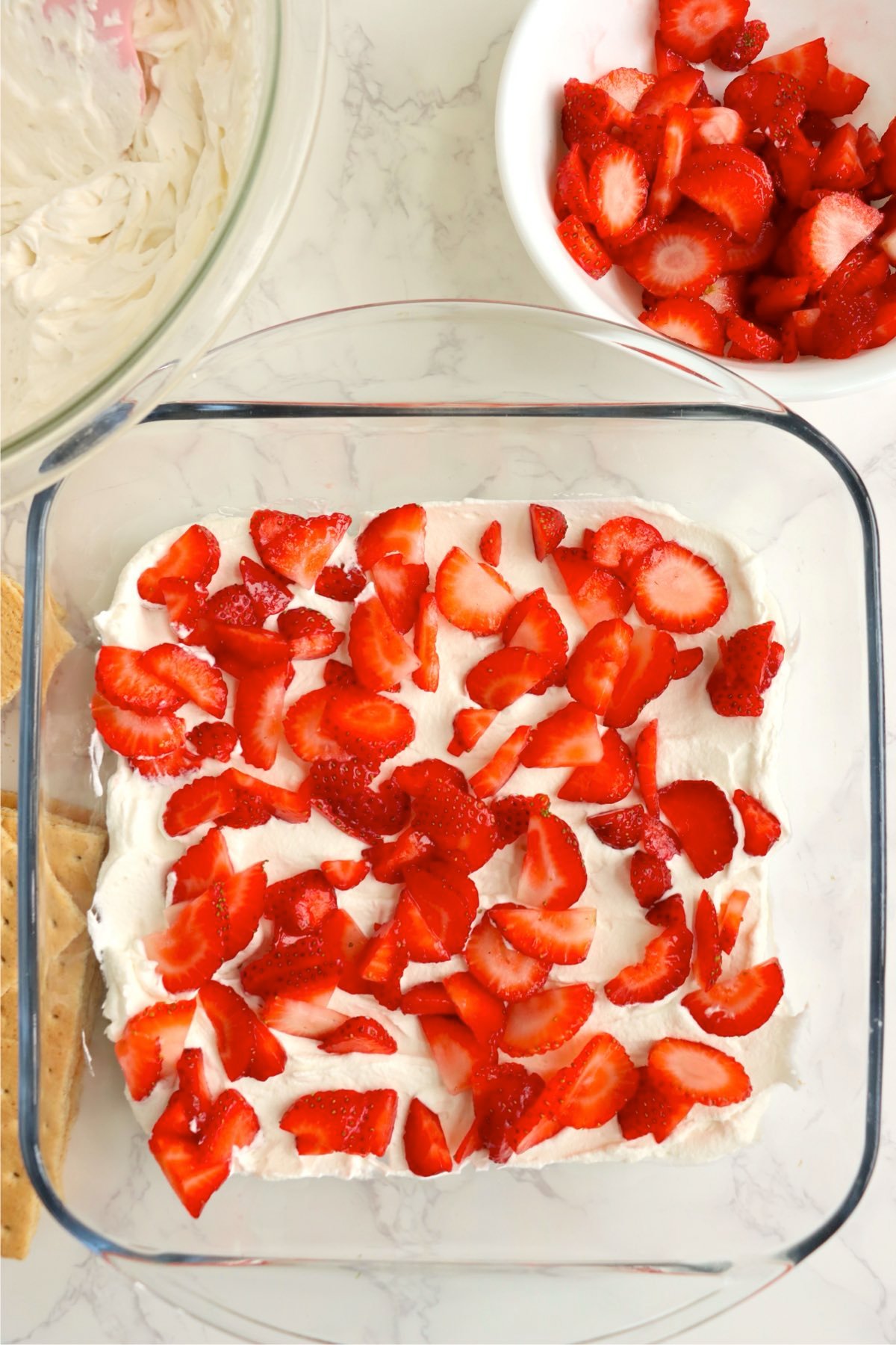 Sliced strawberries scattered over the whipped cream layer.