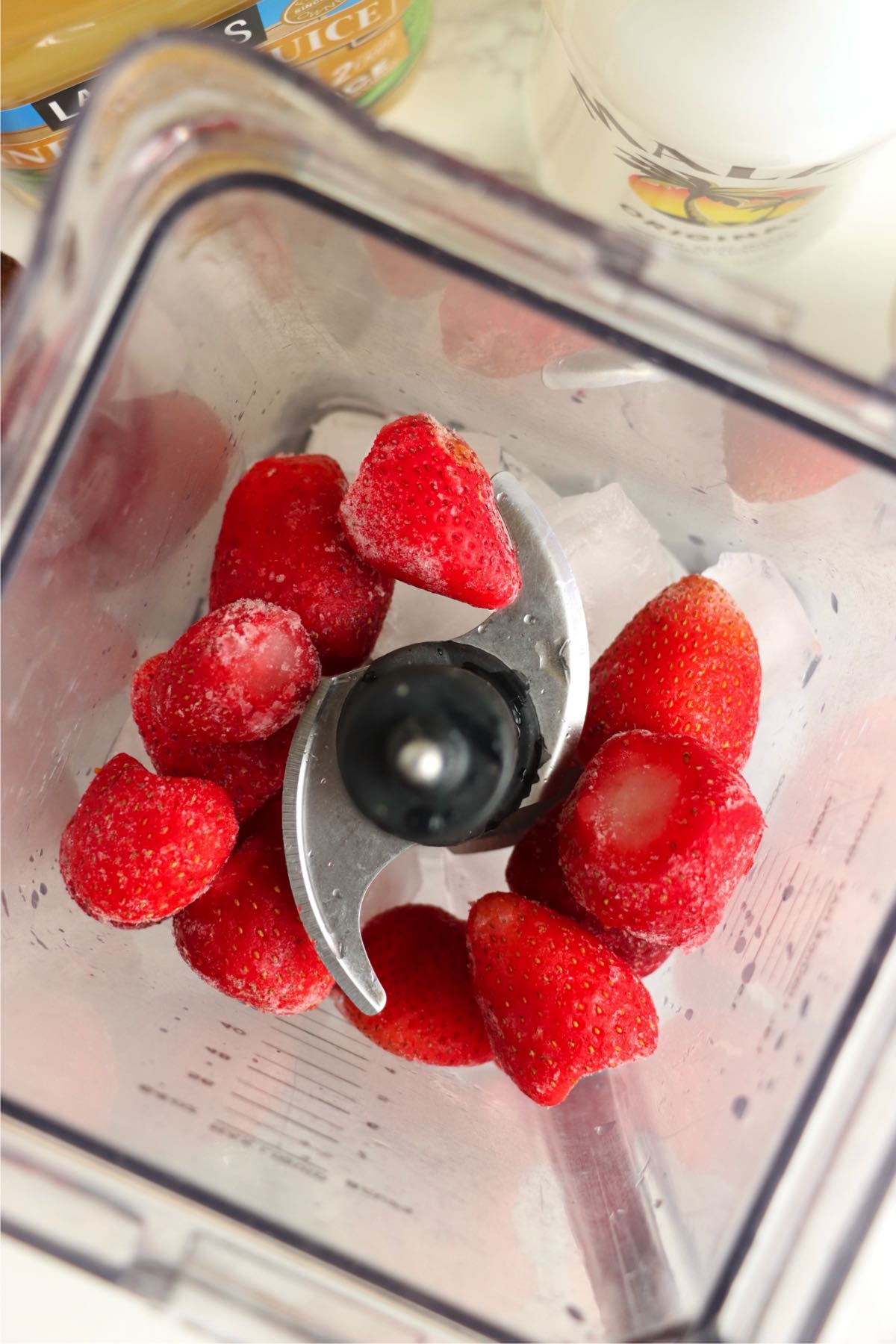 Frozen strawberries and ice inside a blender.