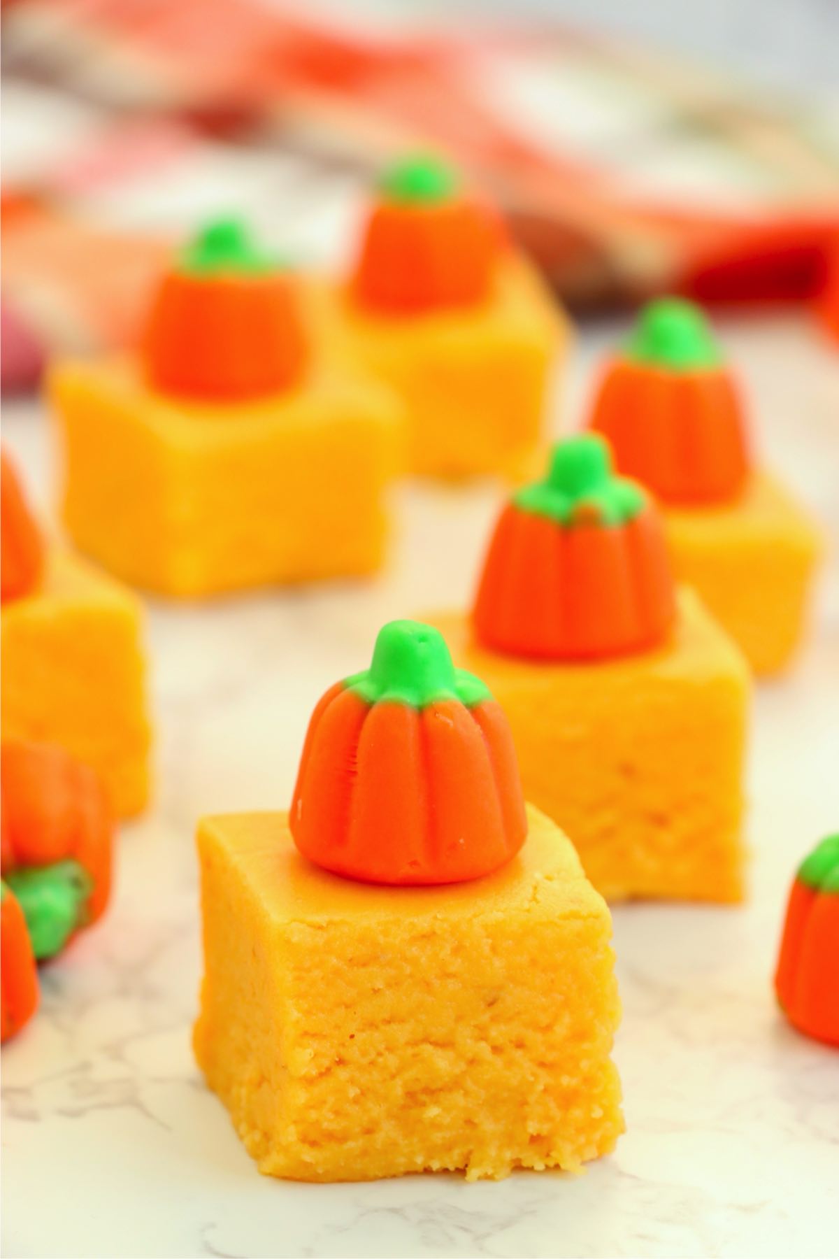 Pumpkin fudge squares decorated with candy pumpkins arranged in a group for serving.