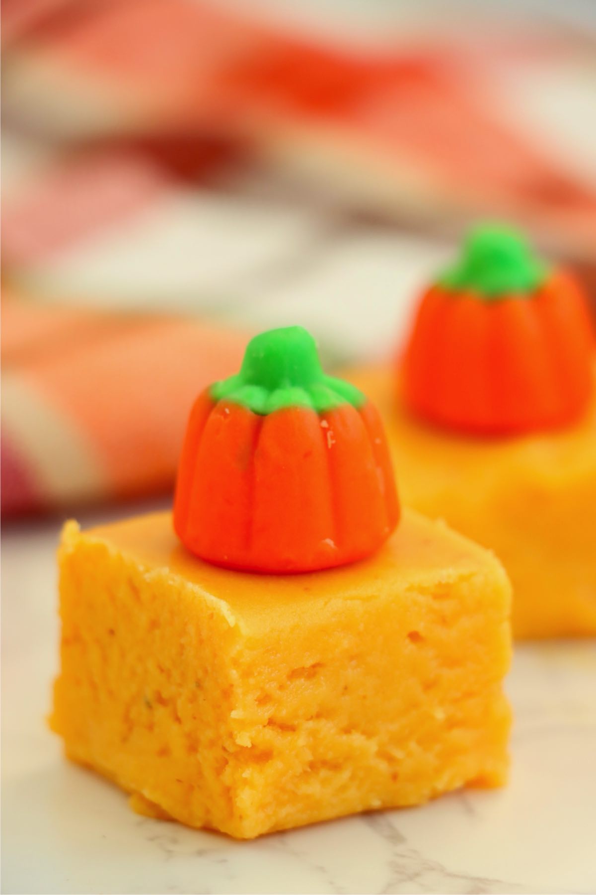 Single square of pumpkin fudge topped with a candy pumpkin.