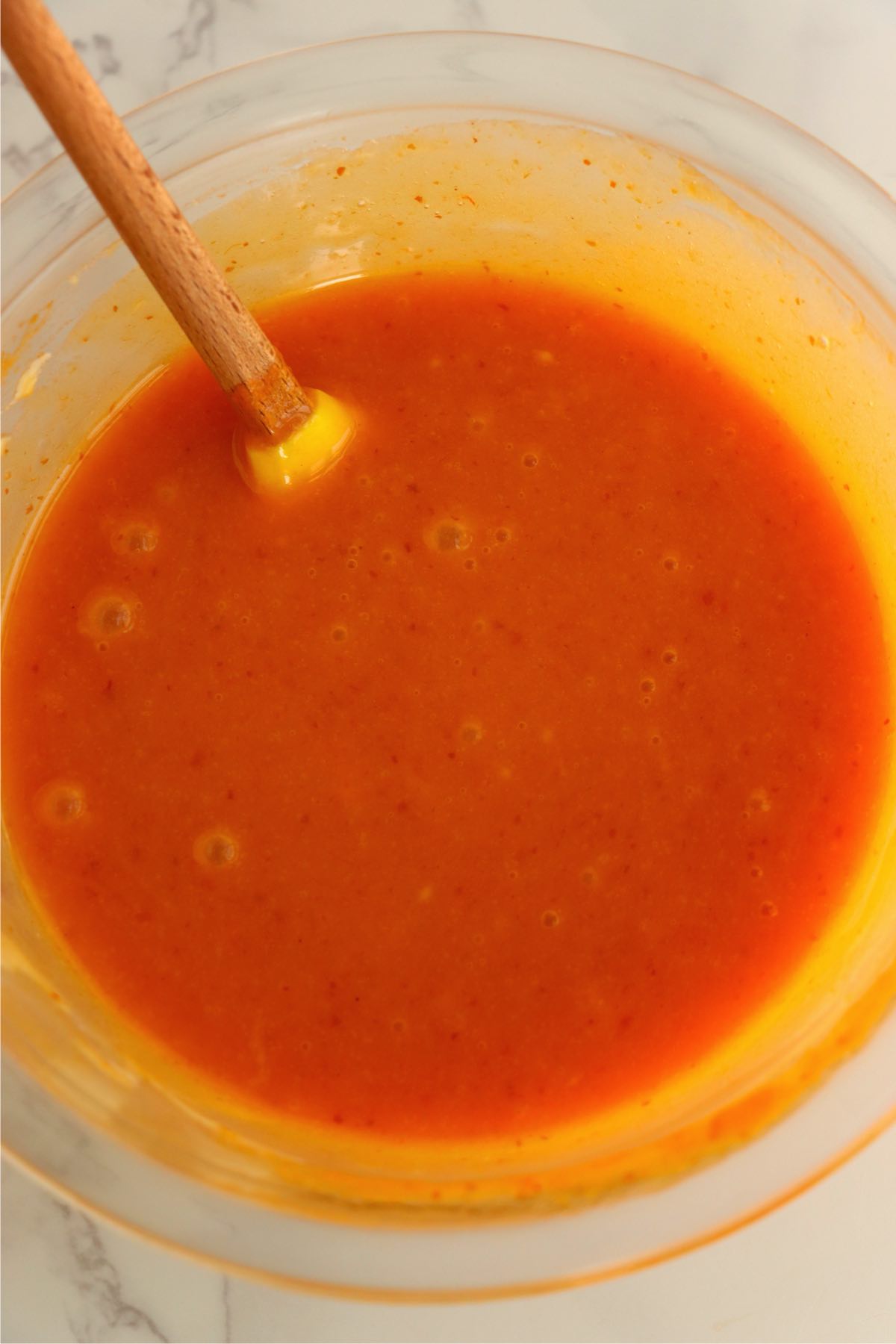 Pumpkin puree and melted white chocolate fully combined into a creamy orange mixture.