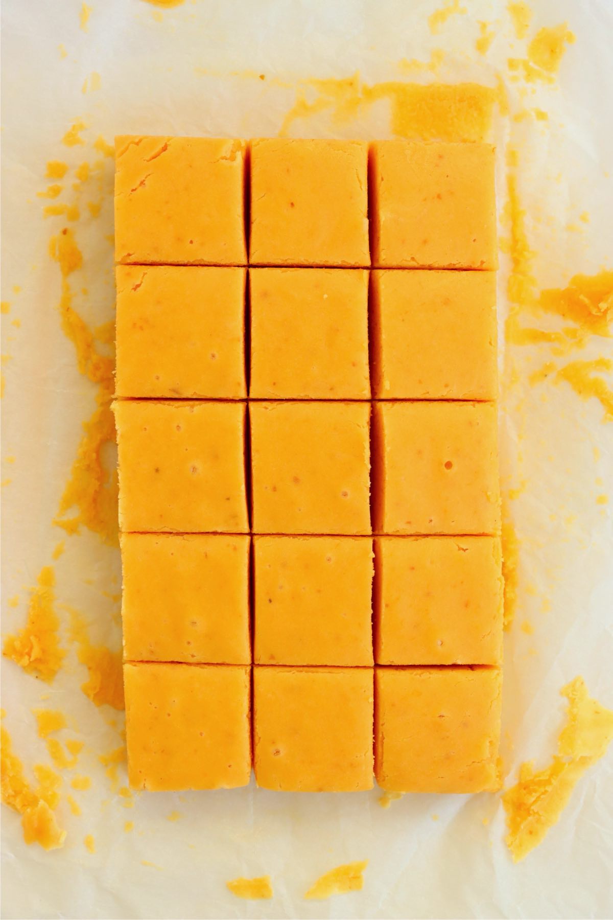 Pumpkin fudge cut into neat squares on parchment paper.