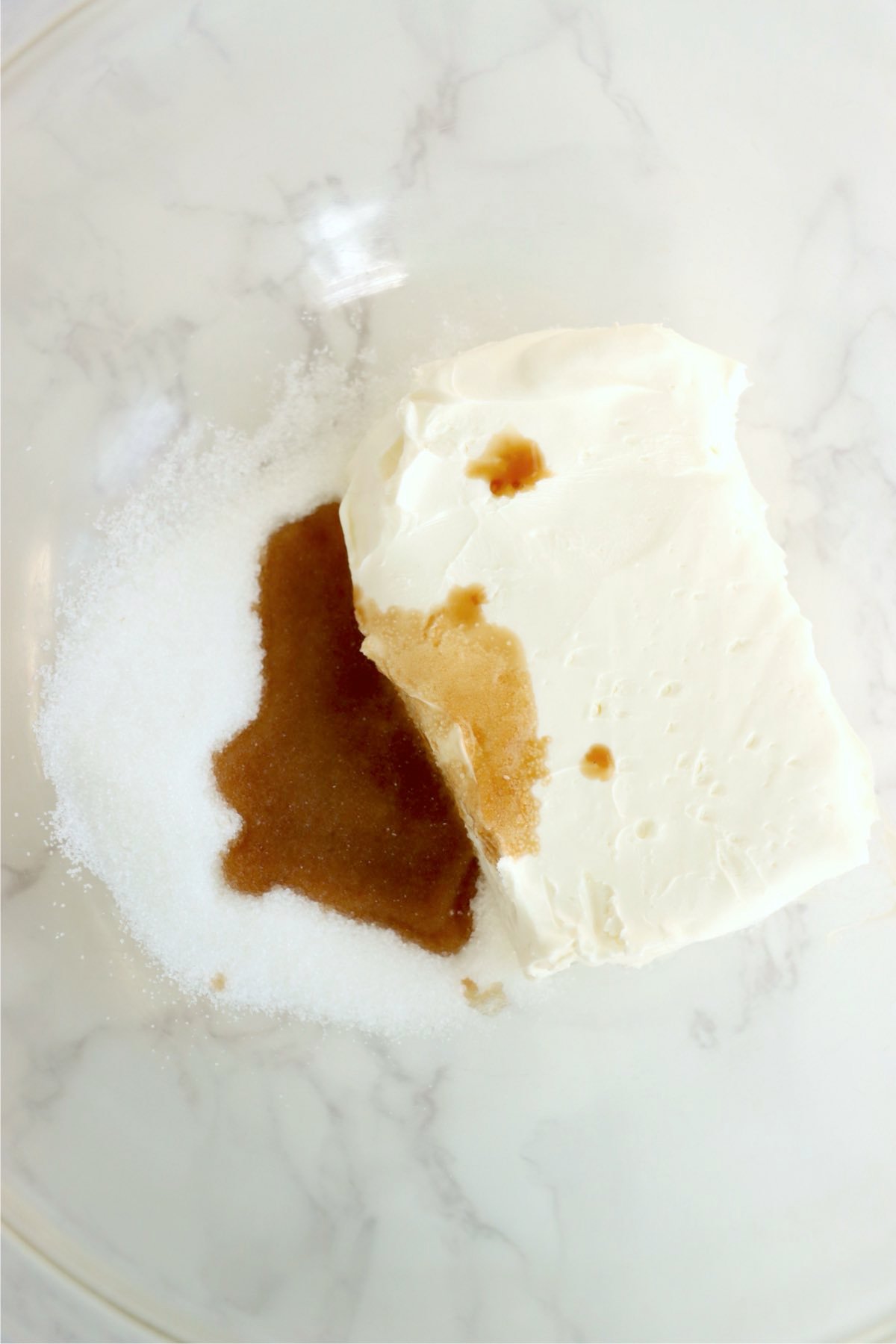 Cream cheese, sugar, and vanilla extract in a bowl before blending into a smooth filling.