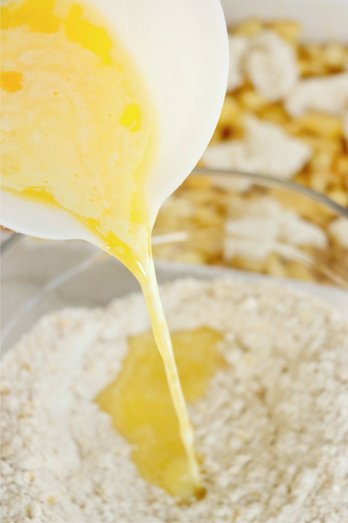 Melted butter being poured into a bowl of oat and sugar mixture for the topping.