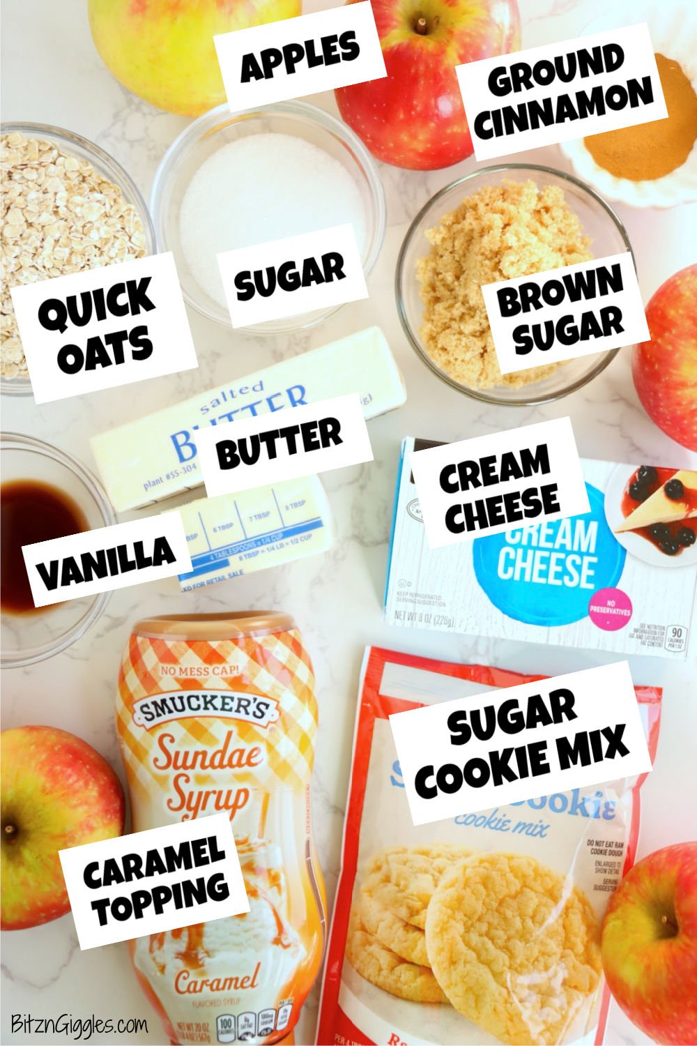 Baking ingredients including apples, oats, sugar, butter, cream cheese, caramel syrup, and sugar cookie mix on a marble surface.