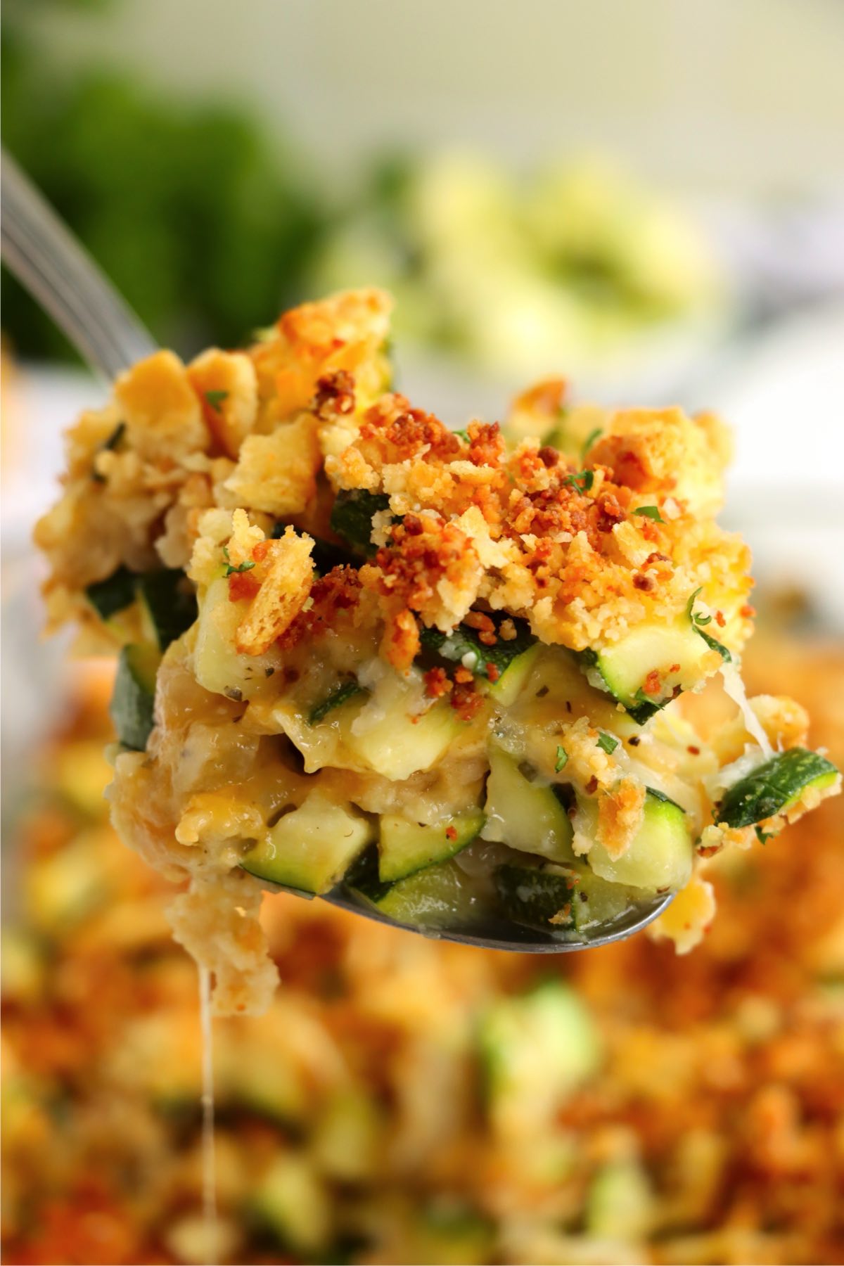 Spoonful of cheesy zucchini bake showing melted cheese, tender zucchini, and crunchy topping.