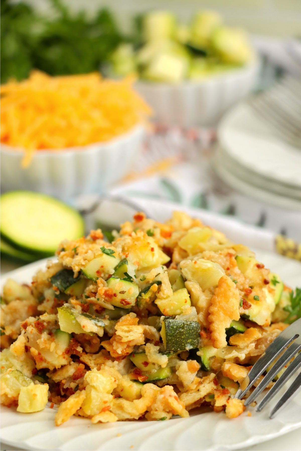Close-up of a serving of cheesy zucchini bake on a white plate, highlighting the golden crust and diced zucchini.