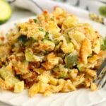 Serving of cheesy zucchini bake on a plate with a fork, featuring chunks of zucchini and melted cheese.