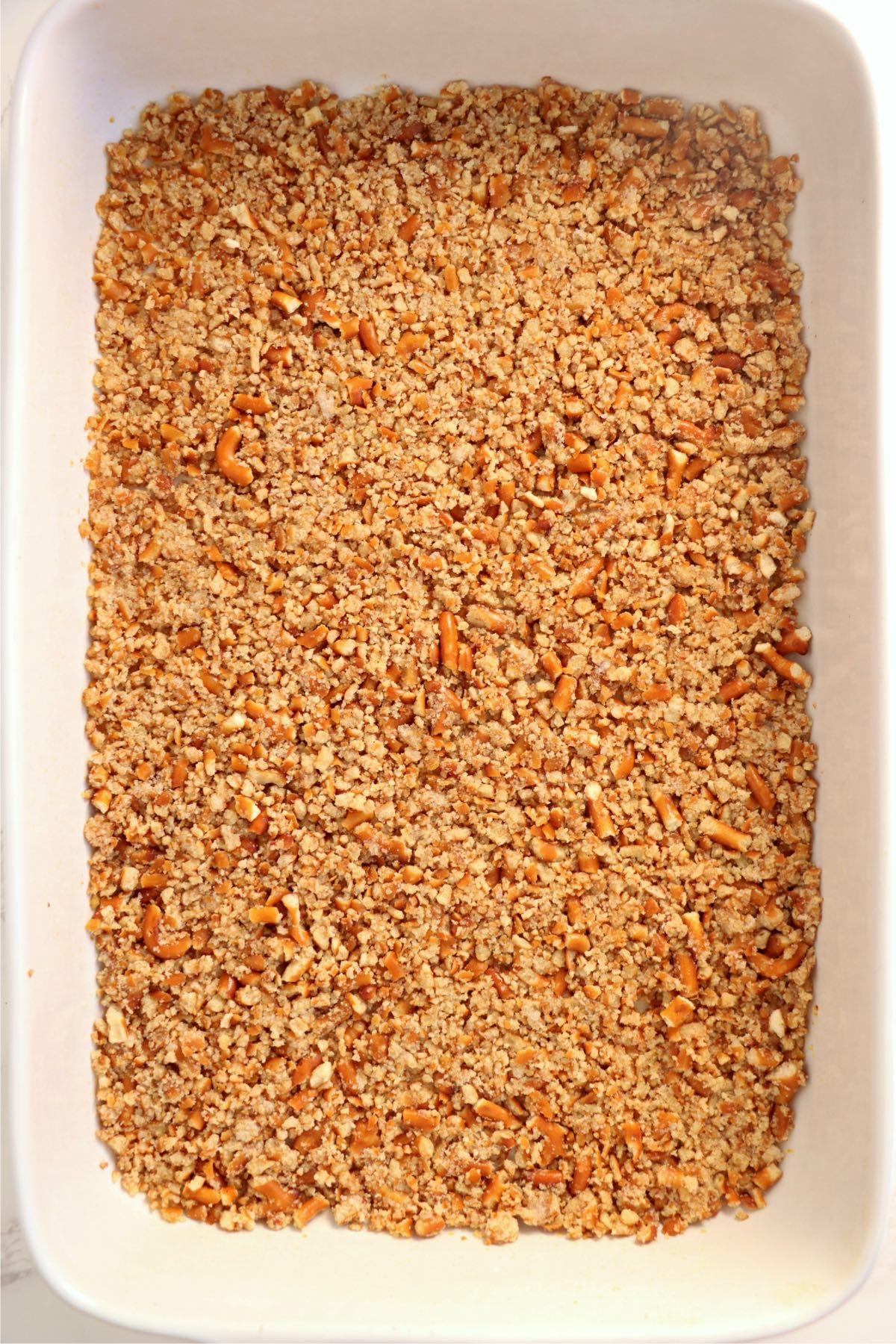 Pretzel crust mixture evenly pressed into the bottom of a baking dish before baking.