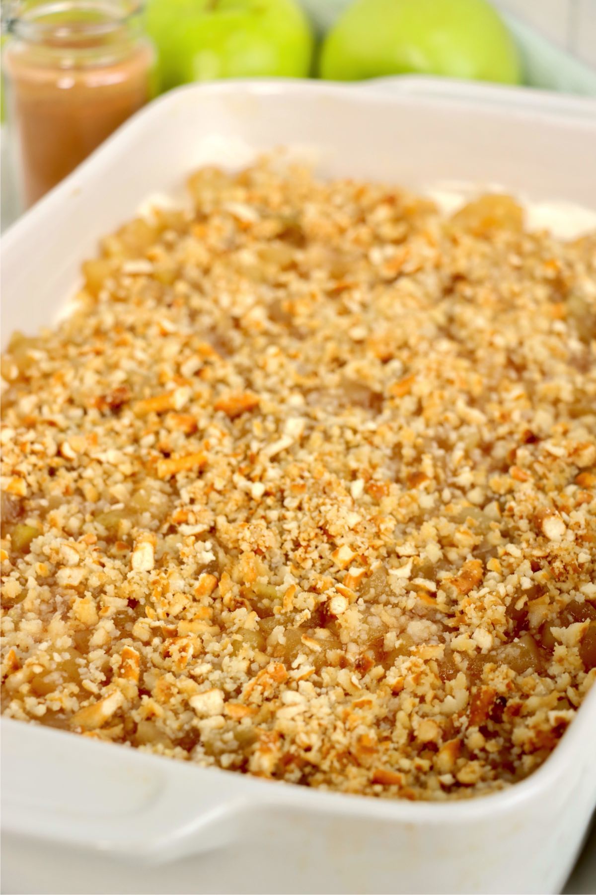 Dessert with diced apples and golden pretzel crumbs, ready to chill before serving.